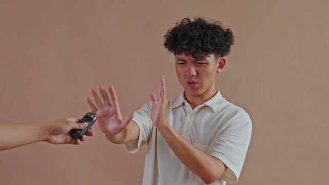 Young man rejecting vape device offered by hand studio background