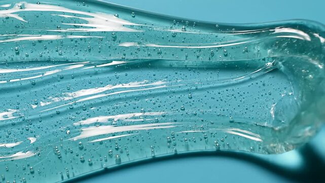 Clear cosmetic gel texture with air bubbles on blue background