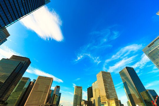 Modern skyscrapers in Tokyo glowing in the late afternoon sun under a clear blue sky.