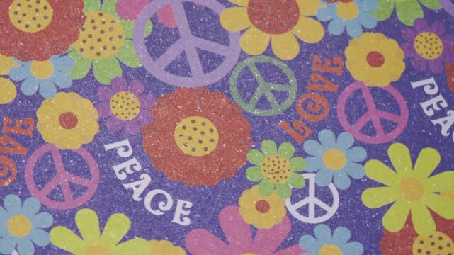 Top view of rotating retro peace and love flower pattern on purple paper, Vibrant 60s style background with moving flowers and peace symbols, Dynamic hippie culture pattern with peace signs