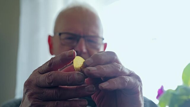 Man rotating bitcoin indoors in daylight as camera rises gently in slow motion