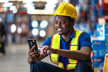 Obraz premium Focused factory worker using mobile internet on smartphone in large warehouse. Concept of smart technology connection and modern business communication.