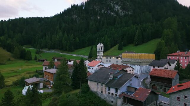 Thusis village houses surrounded by green mountains and dense forest in the Alps. aerial