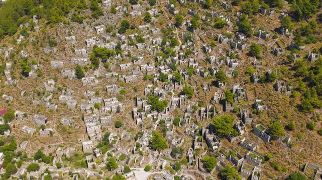 Kayakoy, Turkey. Drone view of abandoned stone architecture in Levissi ghost town on mountain slope, roofless houses and crumbling walls after 1957 earthquake and decades of neglect.. Aerial View, Ma