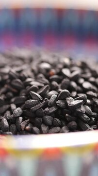 Black cumin seeds are shown in a decorative bowl