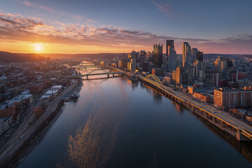 Fototapeta premium Downtown skyline aerial panorama at sunset with river water reflecting colorful sky and bridges crossing urban cityscape with tall buildings and roads