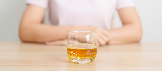 woman with glass of whiskey on table, suffering from alcohol addiction and alcoholism concept. depicting emotional distress, depression, substance abuse problem, unhealthy lifestyle and mental health