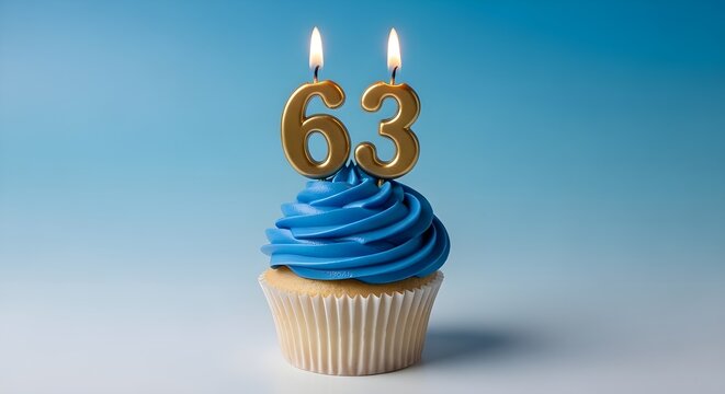 A blue frosted cupcake with lit candles forming the number 63 on top for a 63rd birthday celebration