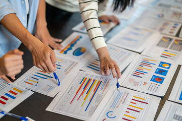 Close up of business consultant team hands pointing at data summary charts with pens on table, Corporate data analysts discussing financial strategy, market research and investment planning concept © Art_Photo