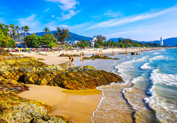Tropical Patong Beach Phuket Thailand tourists people parasol palms rocks. © Arkadi