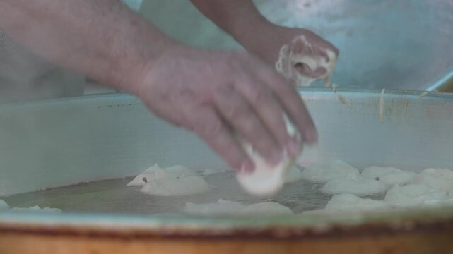Close-up video showing a cook dropping lokma dough into hot oil during the preparation of traditional Turkish lokma dessert. Lokma is a fried sweet dough ball dessert distributed as charity in Islamic