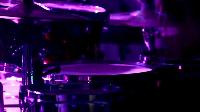 The musician is playing Rock sound Drummer rehearsing on drums in a dark studio and beats drums and cymbals with illuminated by the golden light  HD