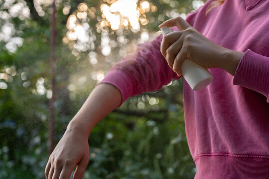 Hand applying insect repellent mosquito insecticide spray to kill flies bugs and mosquitoes on skin outside. Malaria zika virus and dengue fever prevention. Protective measures