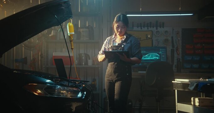 Professional Female Mechanic Works in Workshop, Running Computer Diagnostics Connected Laptop. With Tablet in Hand, Woman Leverages Artificial Intelligence Detect Faults and Evaluate Engine Data.