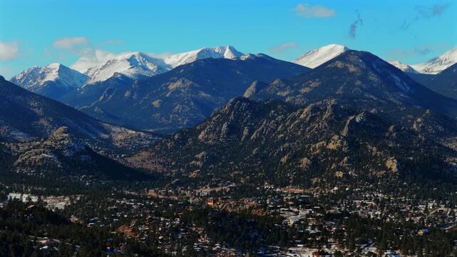 Estes Park mountain town Colorado aerial drone Rocky Mountains National Park landscape afternoon sunset fresh snow clouds blue sky sunny Lumpy Ridge Twin Owls rock formation Mummy Range circle right