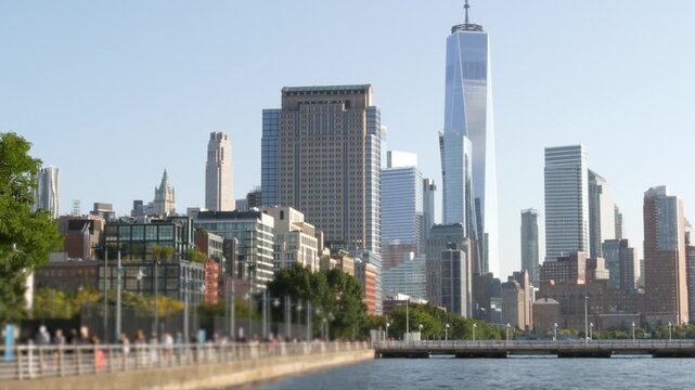 New York City Manhattan downtown financial district skyline, United States. Urban waterfront cityscape, World Trade Center skyscraper building, Hudson River Park, people walk on riverfront promenade.