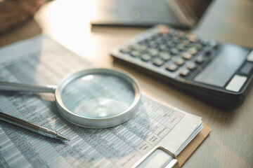 Corporate finance concept with magnifying glass over financial report, calculator and documents on...
