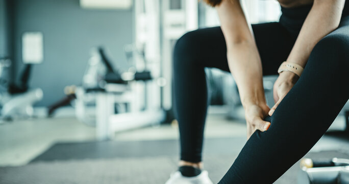 Female athlete holding sore calf muscle after intense workout, representing delayed onset muscle soreness and post workout pain. Concept of fitness recovery, inflammation and sports rehabilitation.