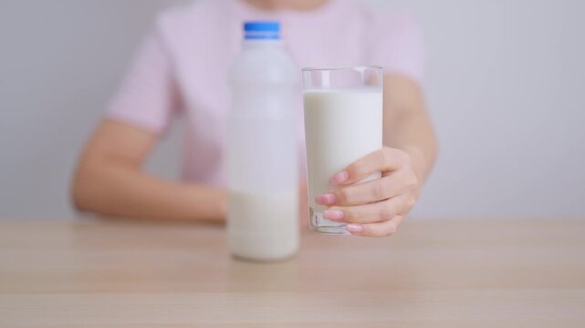 Healthy woman holding glass of fresh milk at home, female drinking milk for calcium and strong bones, high protein, dairy product for healthy lifestyle, wellness and daily routine concept