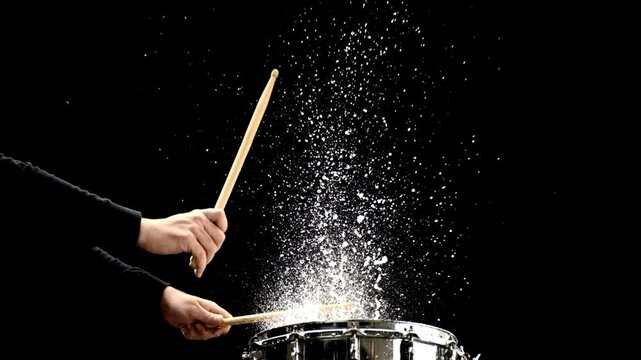 Close-up drummer plays with water splashing Drummer In Concert in black clothes sits behind a drum kit cymbals. beats with drumsticks on a hi-hat cymbal song