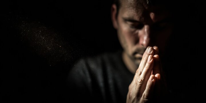 Religious Man Praying With Hands Together in Dark Church Setting for Spiritual Advertising Background with Copy Space and Dramatic Lighting