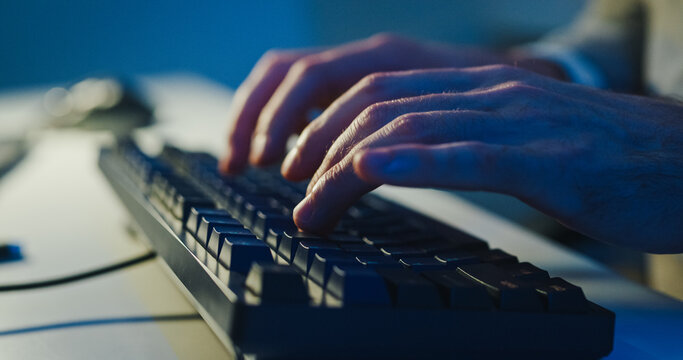 Closeup young adult male freelance developer typing write prompt AI bot app program nomad terminal coding at office night. Artificial intelligence dashboard, robotics user interface, machine learning.