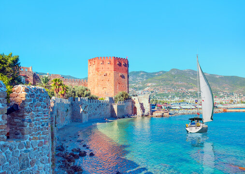 Landscape of ancient shipyard near of Red Tower (Kizil Kule tower) with lone yacht - Alanya peninsula, Turkey