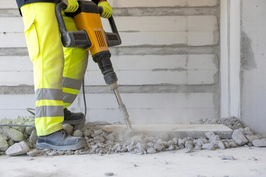 Construction worker breaks up concrete with a powerful jackhammer
