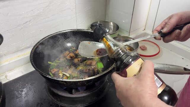 Cooking food in a wok at home kitchen, with pieces of battered ingredients deep frying in hot oil while being stirred with a metal spatula, showcasing energetic Chinese home cooking in Xi'an, China.