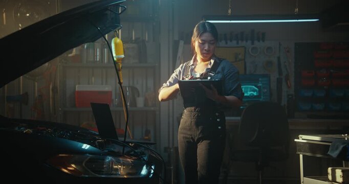 Asian Auto Mechanic Conducts High Tech Car Inspection, Linking Laptop to Onboard System. Using AI Software on Tablet, Girl Compares Real Time Readings With Standard Indicators to Resolve Malfunction.