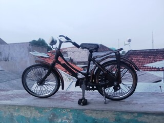 Fototapeta premium Miniature Vintage Bicycle on Rooftop with Urban Background