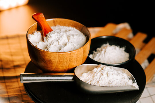 Flour surrounded by measuring tools on a kitchen counter with a soft glow in the background