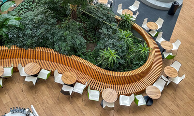 High angle view of modern indoor cafe with circular wooden bench and lush green plants © reddish