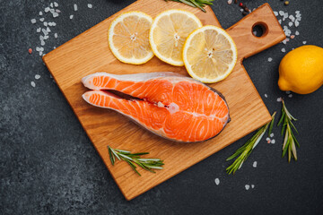 Fresh salmon fillet with lemon slices on a wooden cutting board