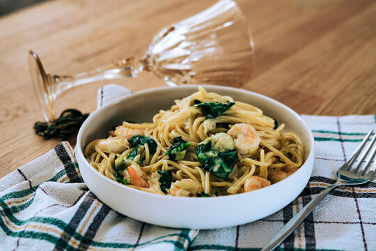 spaghetti with shrimp,  spinach and creamy white sauce on tustic wooden table, mediterranean İtalian cuisine concept