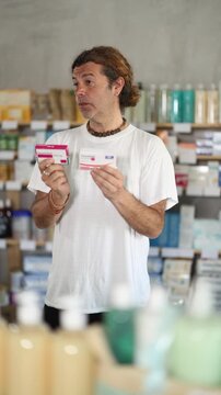 Adult man buyer chooses box of paracetamol tablets in pharmacy 