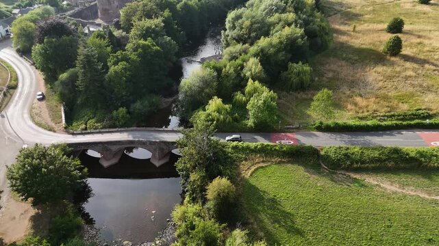 Skenfrith Castle Herefordshire,flight over the river and ancient bridge towards the Norman Castle on the Welsh border with birds flying by in bright summer sunshine