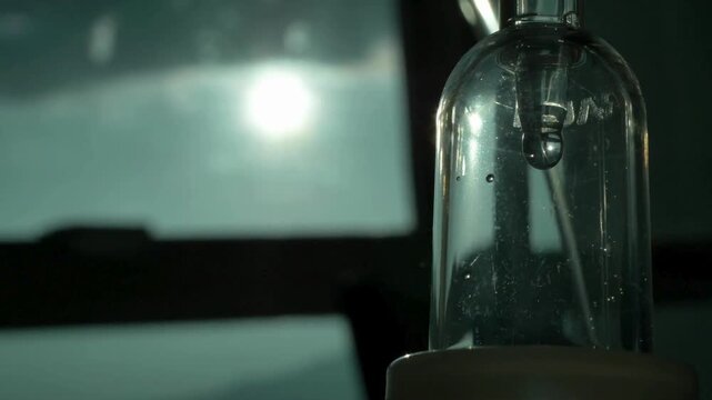 Close-up of intravenous saline solution in medical clinic in light bright interior IV drips through drip chamber NSS drip ready to be infused