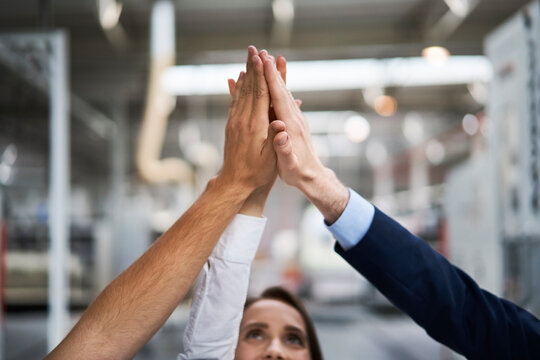 Close-upof businessman and employees high fiving in a factory