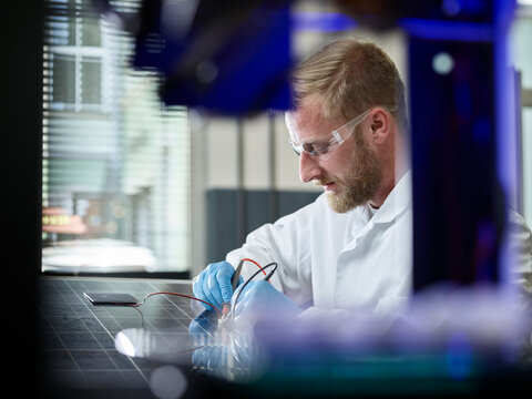 Technician measuring contact of silicon solar cell on solar panel