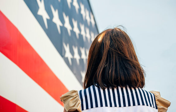 USA, back view of woman in front of Stars And Stripes