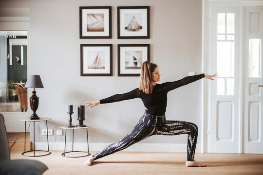 Woman practising yoga at home, warrior pose