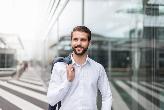 Portrait of smiling young businessman at glass facade