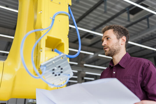 Businessman checking industrial robot in high tech company