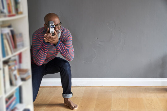 Mature man looking through film camera
