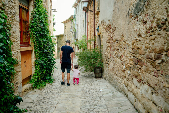 Spain, Catalonia, Peratallada, Medieval Town, Father and daughter walking hand in hand, rear view