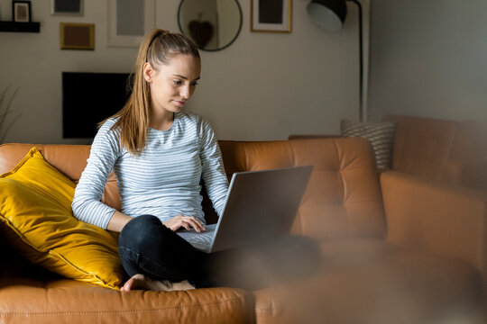 Young woman using laptop on couch at home