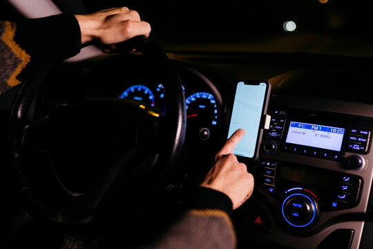 Man using cell phone with road maps in the car at night