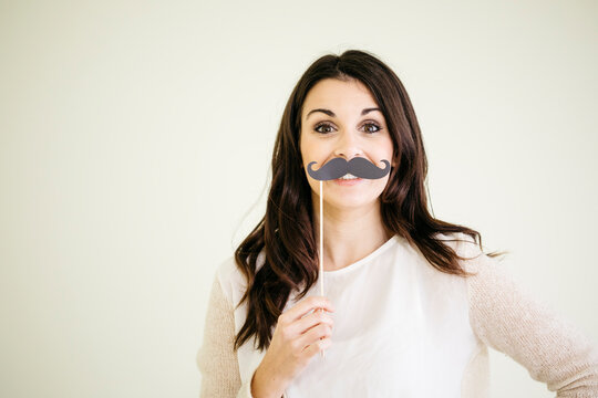 Portrait of young woman with fake moustache