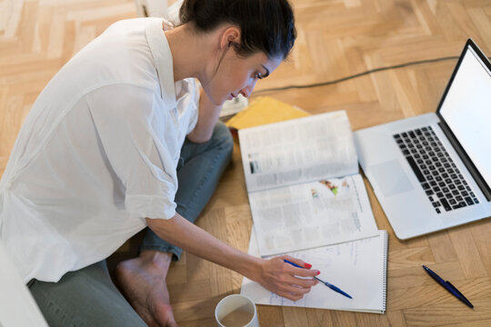 Young woman sitting on the floor looking at notepad
